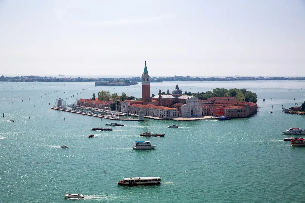 L'isola degli Armeni a Venezia, con il suo campanile e la chiesa, è raggiungibile via acqua. Diverse imbarcazioni navigano nel bacino.
