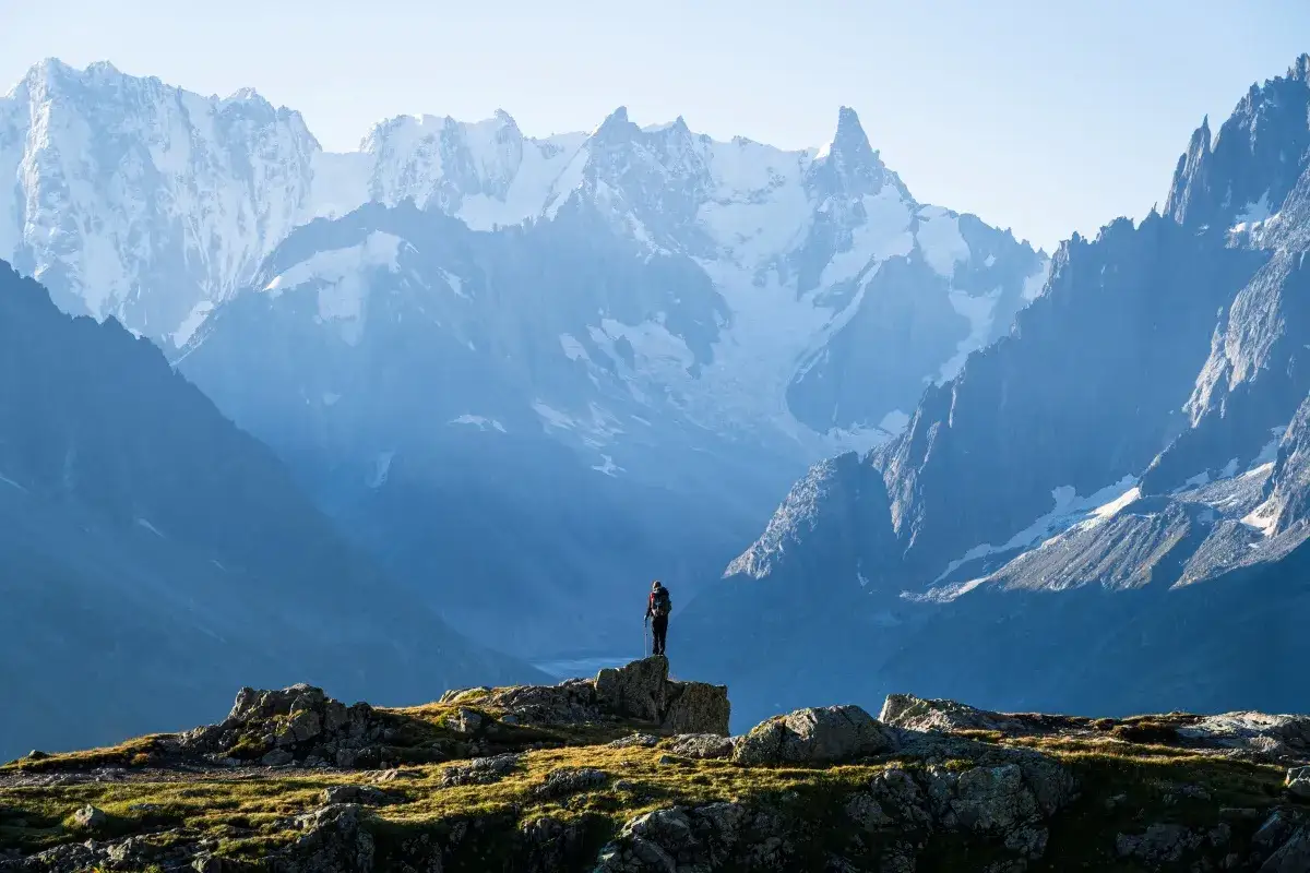 Samotny turysta na szczycie, podziwiający majestatyczne Alpy podczas tour de Mont Blanc.