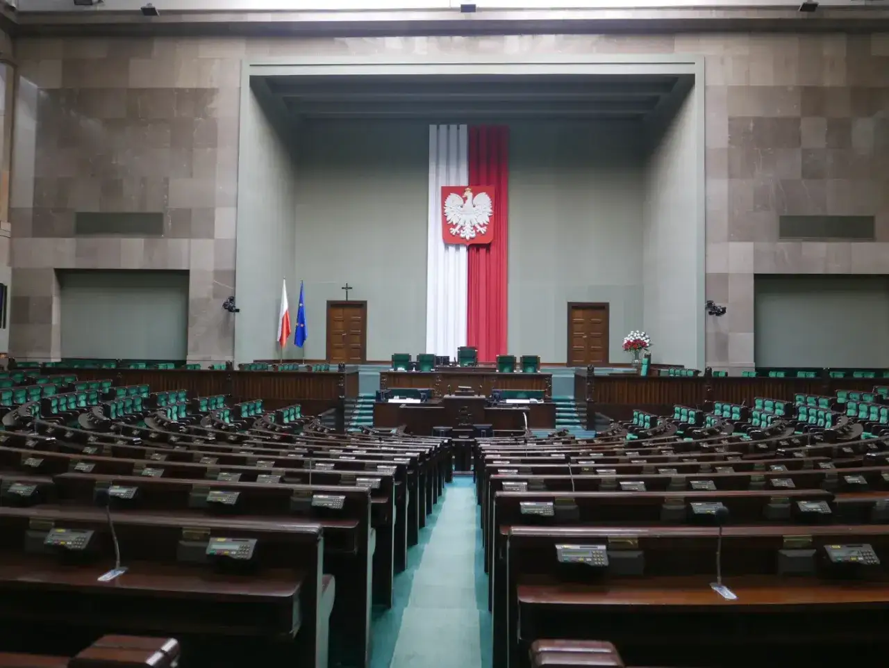 Pusta sala sejmowa z rzędami zielonych foteli i mównicą. Zastanawiasz się, ile zarabia poseł?