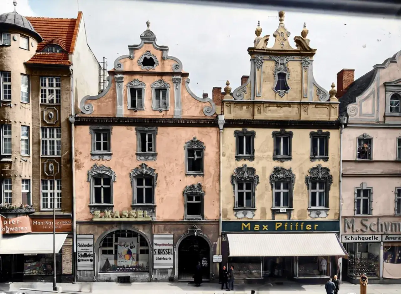 Kolorowe kamienice w stylu historyzmu, świadectwo dawnych **starych miast w Polsce**. Widać szyldy sklepów, np.