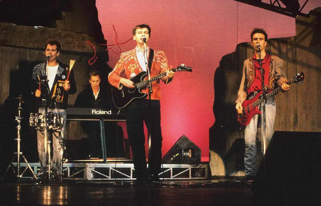 Un groupe australien des ann&eacute;es 80 sur sc&egrave;ne, avec des musiciens jouant de la guitare, de la basse et des claviers.