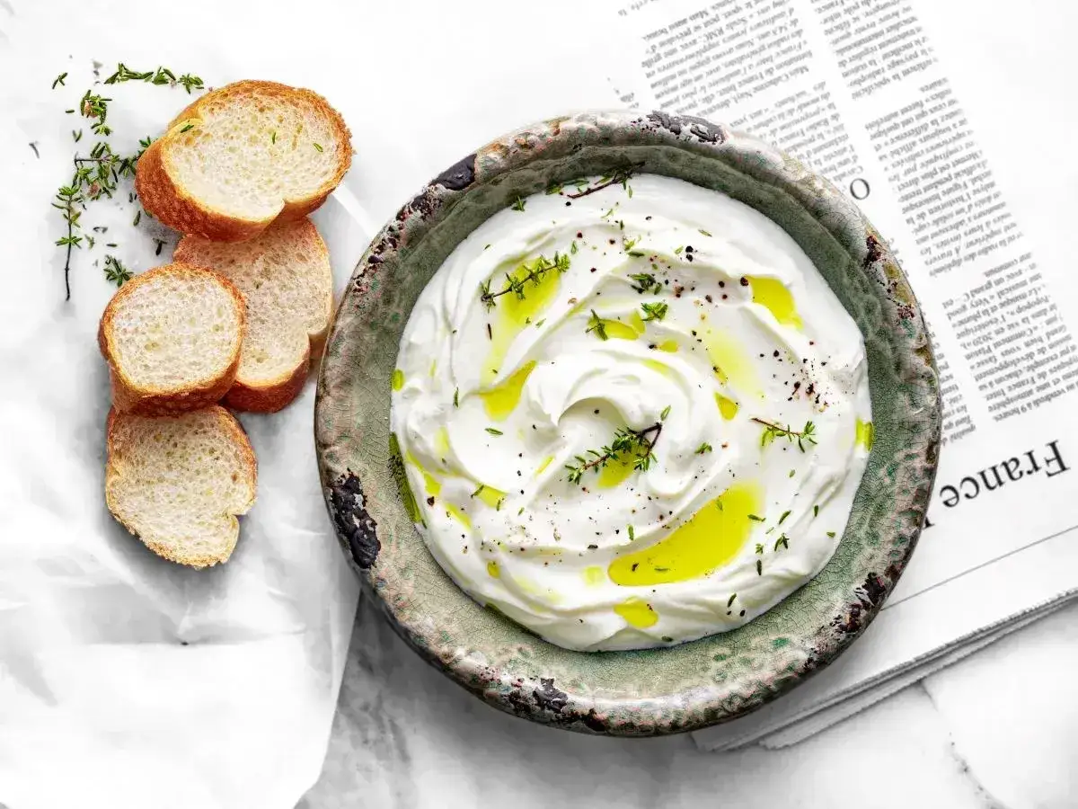 Labneh co to? Kremowy ser z oliwą i ziołami, podany z kromkami bagietki. Idealny na śniadanie.