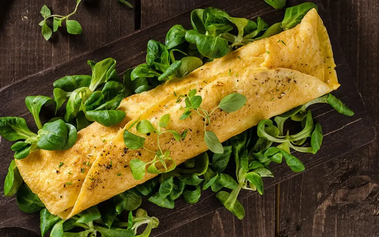 En gyllene omelett med f&auml;rska gr&ouml;na blad, perfekt som nyttiga snacks.