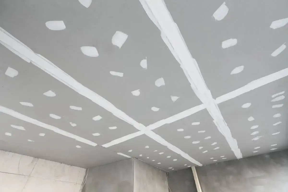 Plafond en cours de finition, avec des bandes de jointoiement blanches sur les plaques de pl&acirc;tre. Travail de coller placo plafond.