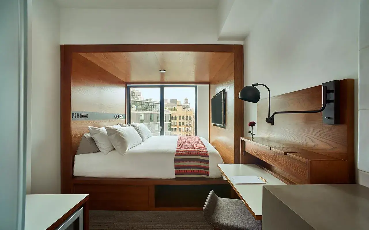 Mysig hotellrum inredning med s&auml;ng, skrivbord och utsikt. Tr&auml;detaljer och modern design.