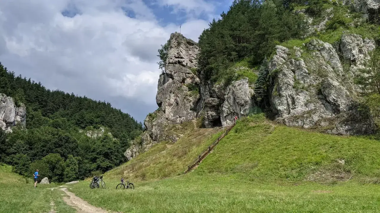 Dolina Kobylańska zachwyca skalnymi formacjami i zielonymi zboczami. Dwie rowerzystki zatrzymały się na chwilę, by podziwiać krajobraz.