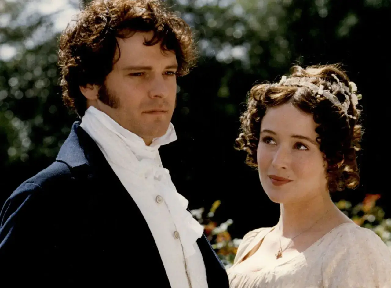 Colin Firth som Mr. Darcy i en scen fr&aring;n filmer och tv-program. Han b&auml;r en m&ouml;rk rock och vit scarf. Bredvid honom st&aring;r en kvinna med lockigt h&aring;r.