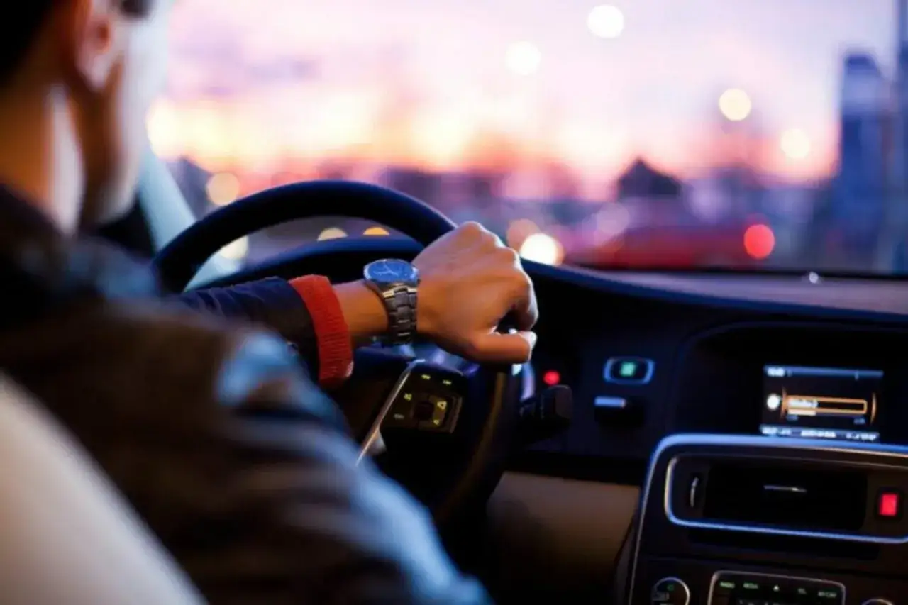 Hombre con reloj conduce de noche, planificar viaje en coche.