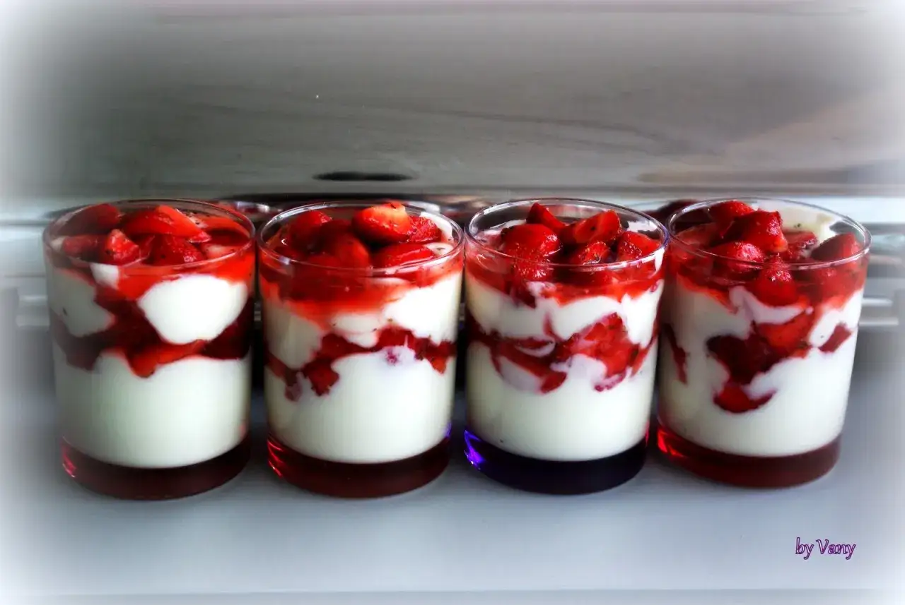 Quatre verrines de dessert léger aux fraises, alternant crème blanche et morceaux de fraises, surmontées de fruits rouges frais.