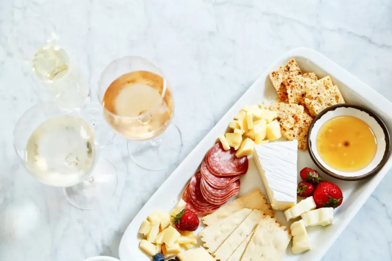 En bricka med ost, kex, salami, jordgubbar och honung, perfekt ost till champagne.