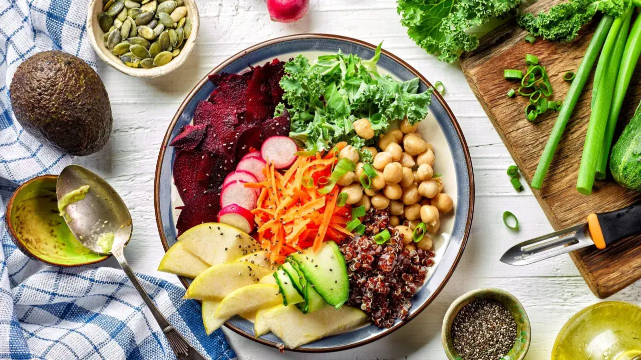 Un piatto colorato con barbabietola, carote, ceci, quinoa, cavolo riccio e mela, perfetto per una dieta equilibrata.