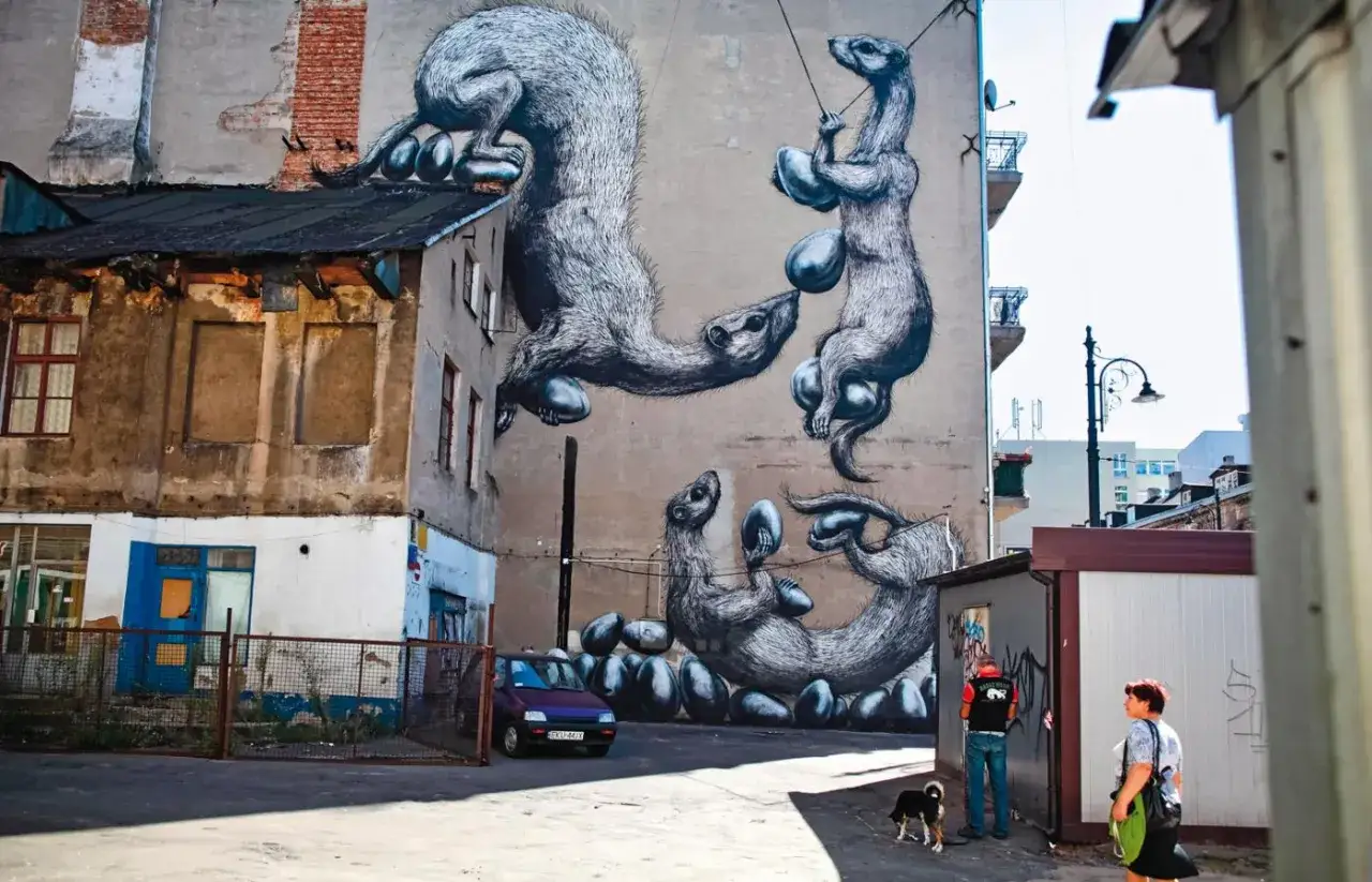 Niesamowite street art graffiti na ścianie kamienicy przedstawia grupę łasic bawiących się jajami.