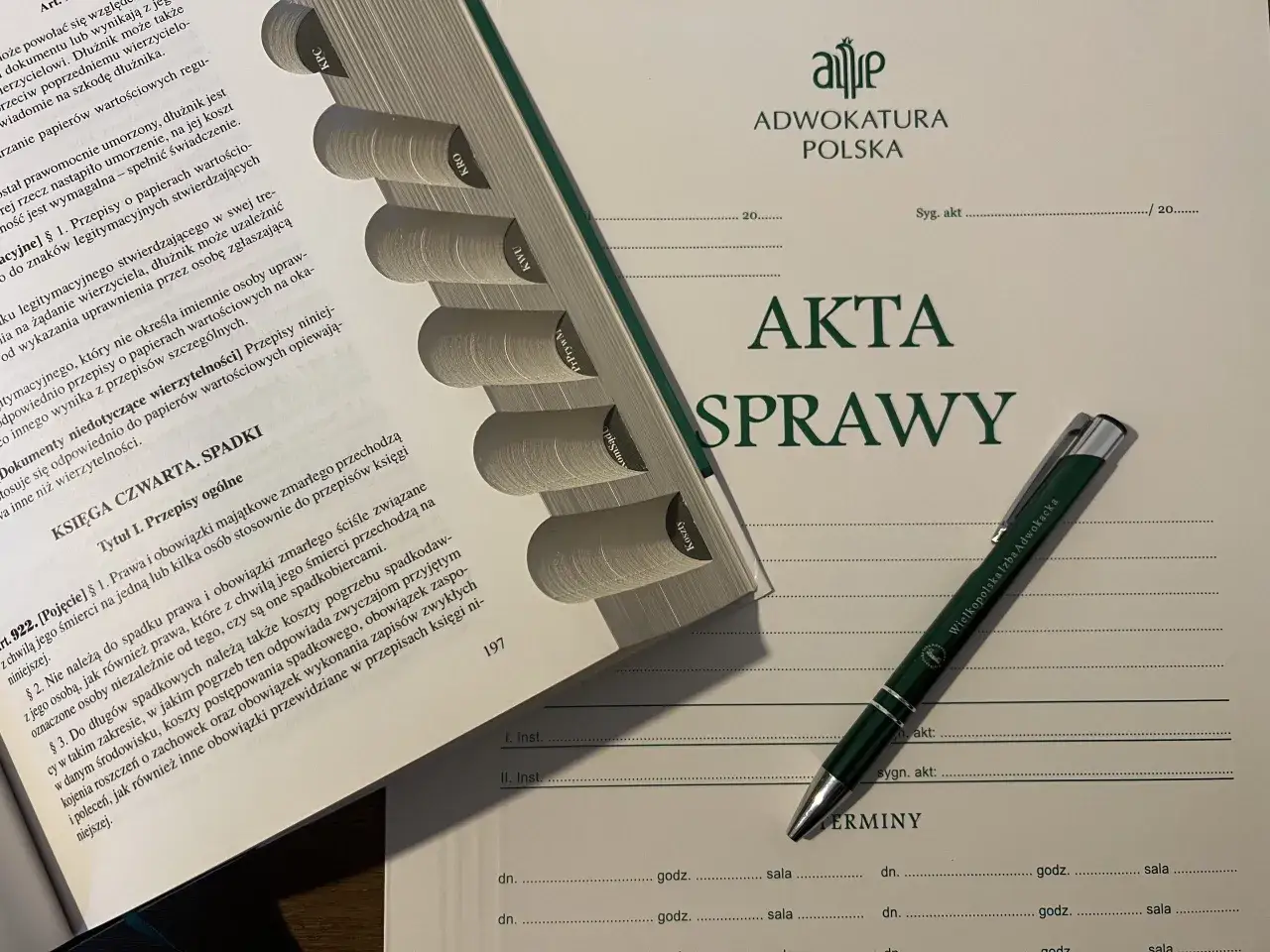 Akta sprawy z zielonym długopisem Wielkopolskiej Izby Adwokackiej. Dokumenty prawne, w tym dotyczące spadk&oacute;w i zrzekania się dług&oacute;w, leżą na stole.