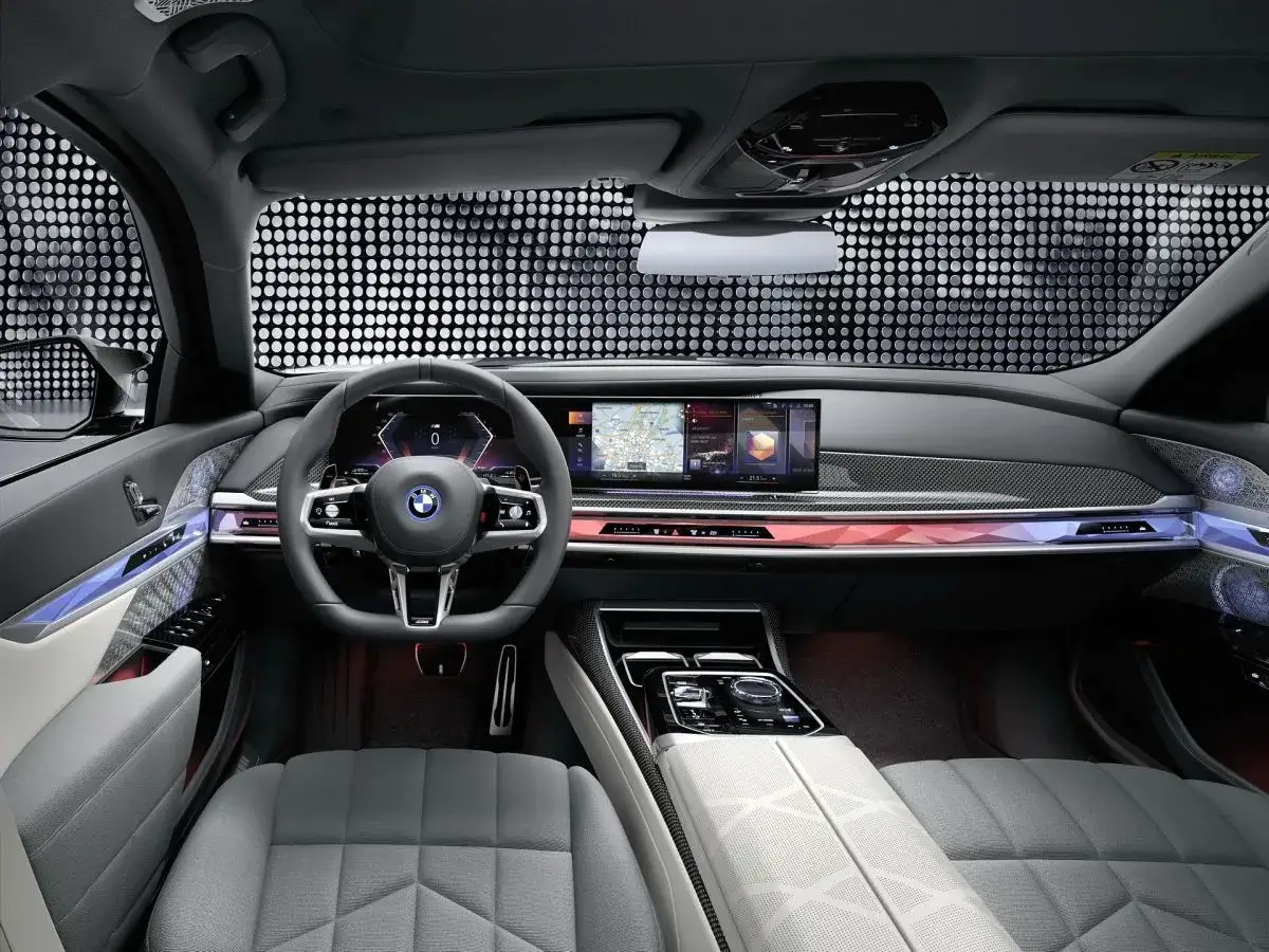 Wnętrze BMW G70: nowoczesna deska rozdzielcza z ekranami, kierownica i ambientowe oświetlenie.