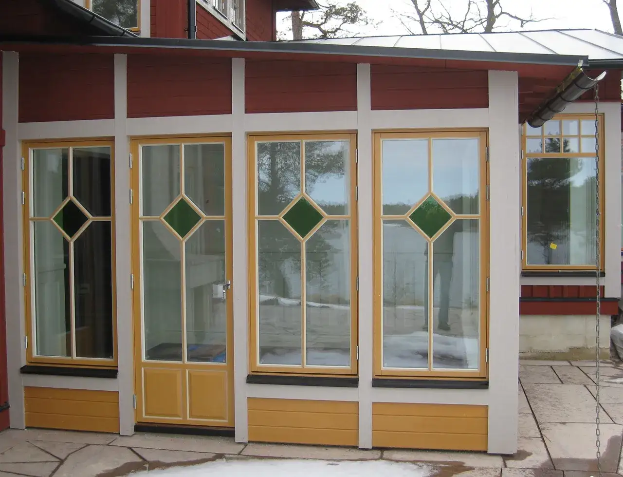 En vacker glasveranda med gula f&ouml;nsterramar och gr&ouml;na detaljer. Perfekt f&ouml;r att bygga en ljus och inbjudande plats.