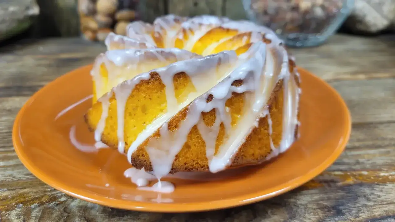 Babka cytrynowa bardzo wilgotna mniam, polana lukrem, wygląda apetycznie na pomarańczowym talerzyku.