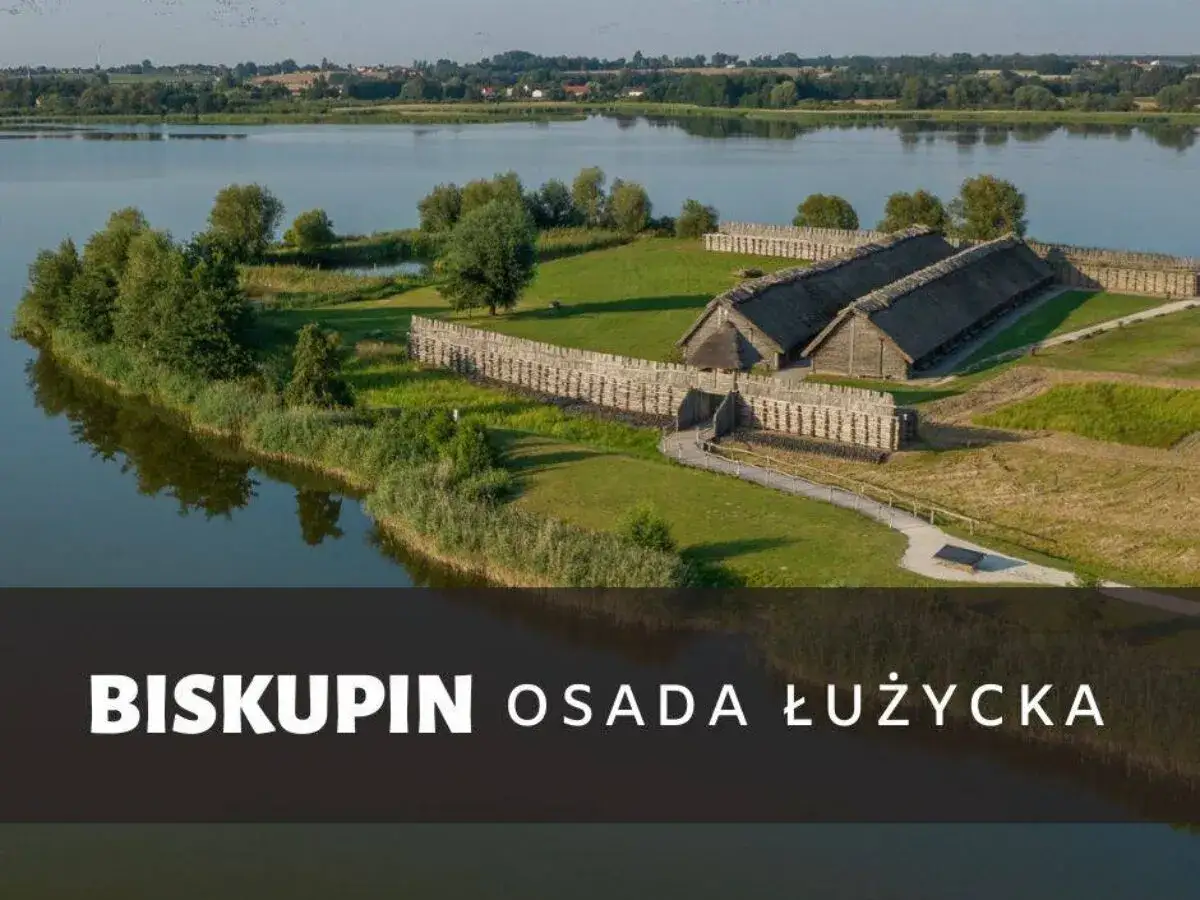Biskupin, osada łużycka, leży nad jeziorem. Widok na drewniane chaty i palisadę.