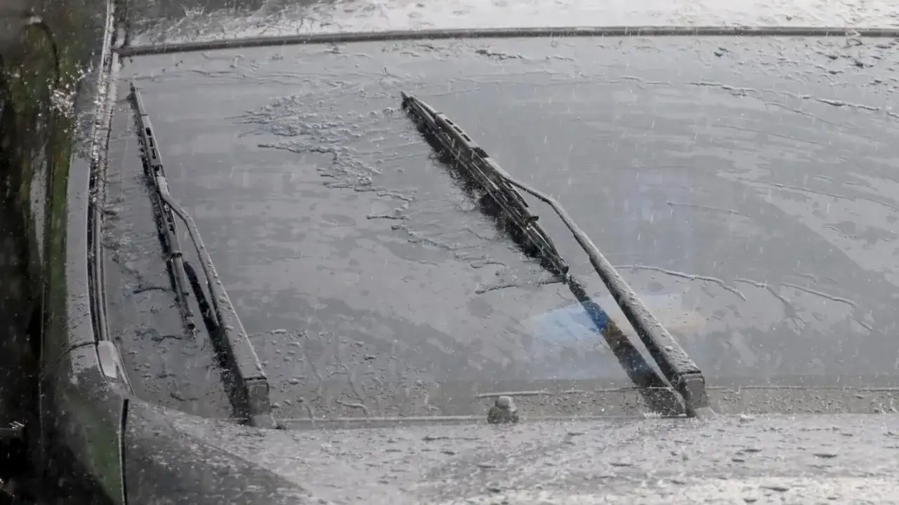 Essuie-glaces sur un pare-brise mouillé par la pluie, essentiels pour le contrôle technique.