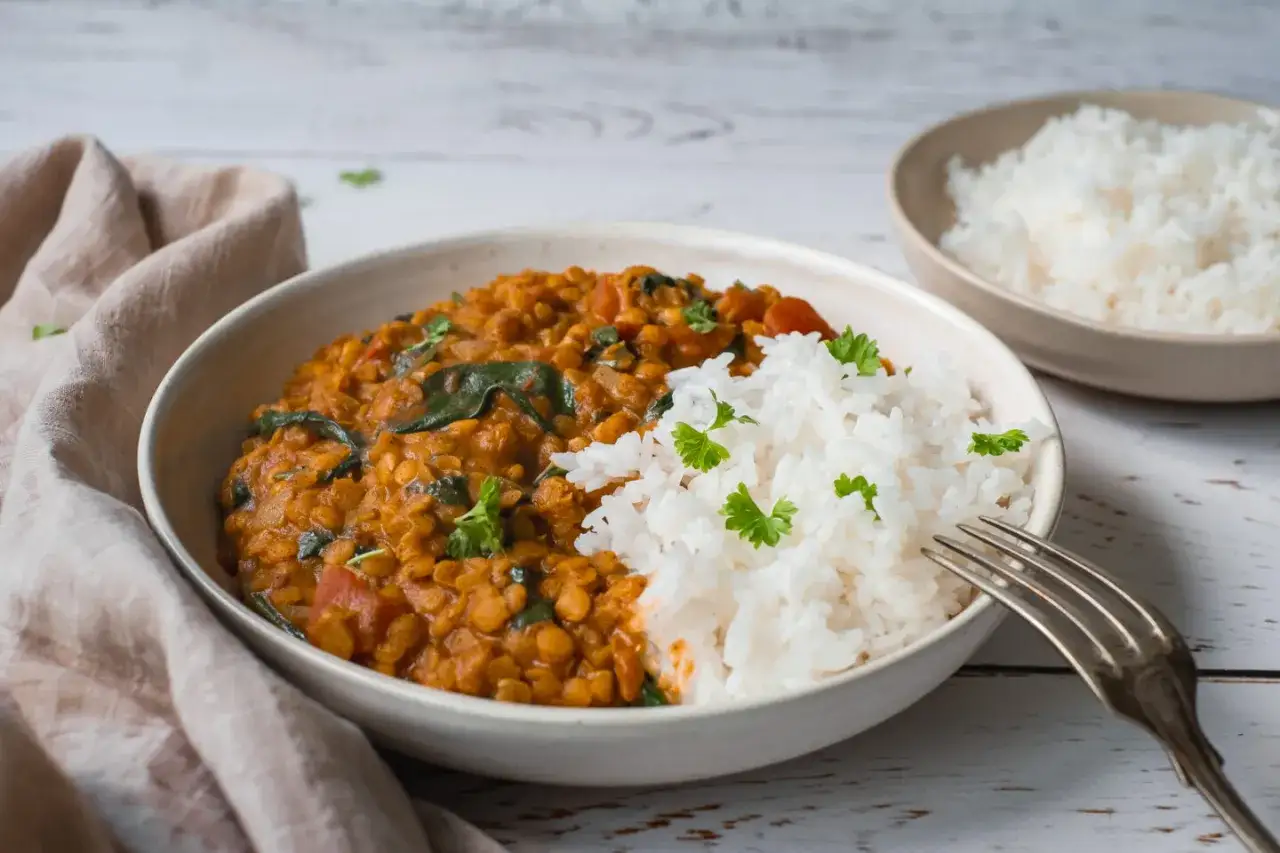 En skål med mustig linsgryta och fluffigt ris, perfekt för ett enkelt linsgryta recept. Garnerad med färsk persilja.