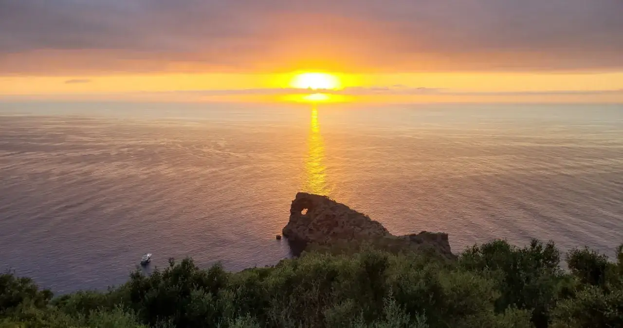 Atardecer espectacular en el mirador de Sa Foradada, con el sol reflej&aacute;ndose en el mar y una roca con un agujero.