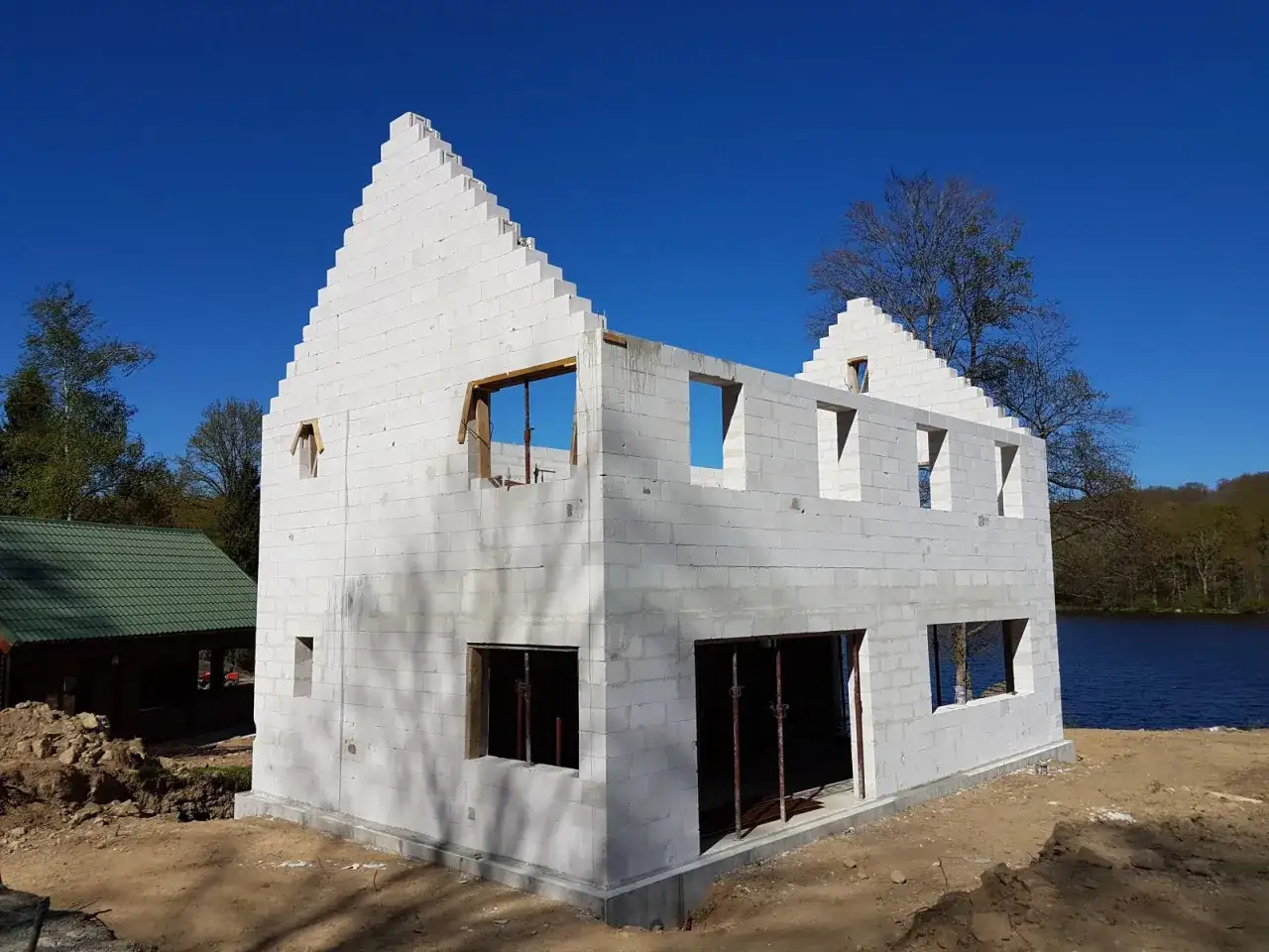Maison en construction, murs en b&eacute;ton cellulaire ext&eacute;rieur, avec des ouvertures pour fen&ecirc;tres et portes. Le soleil brille sur le chantier.