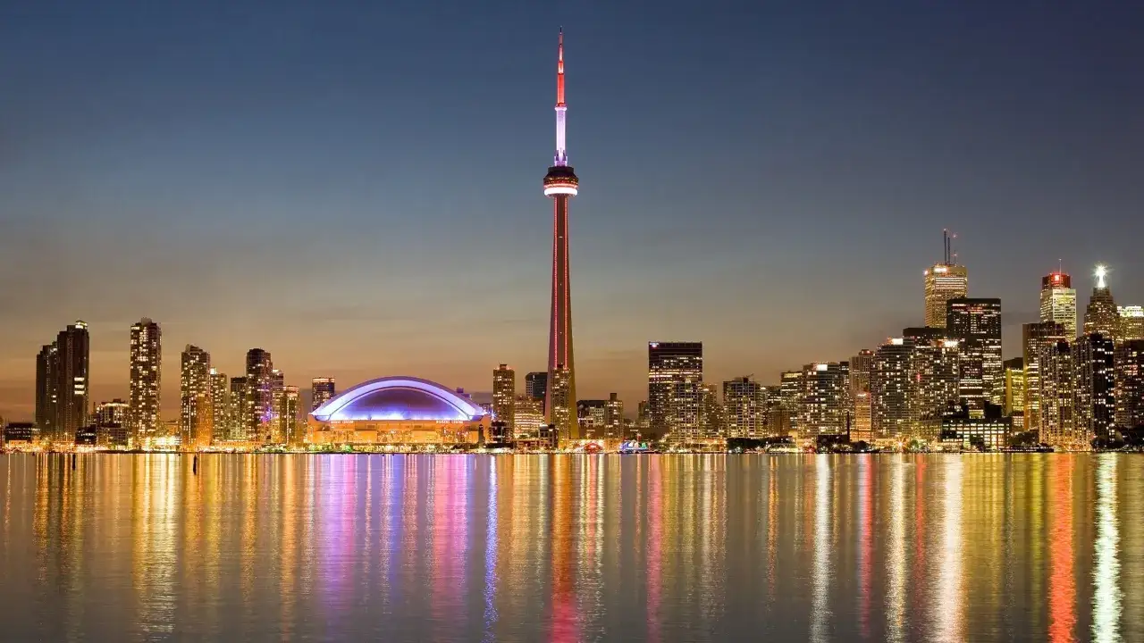 Toronto Skyline bei Nacht mit dem beleuchteten CN Tower. Ein **Toronto must see** mit glitzernden Lichtern auf dem Wasser.