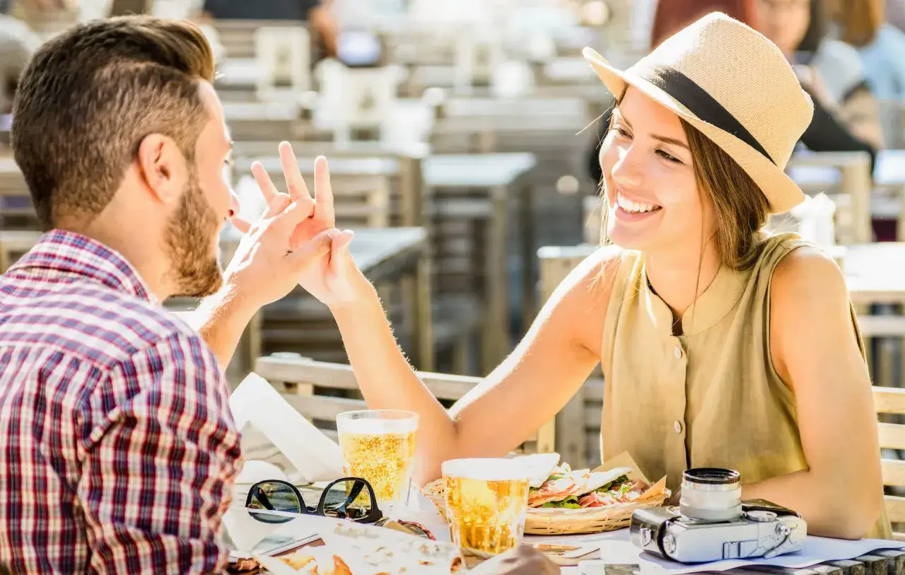 Para, co oznacza skr&oacute;t FWB na Tinderze? Uśmiechnięta para na randce w kawiarni, trzymająca się za ręce.