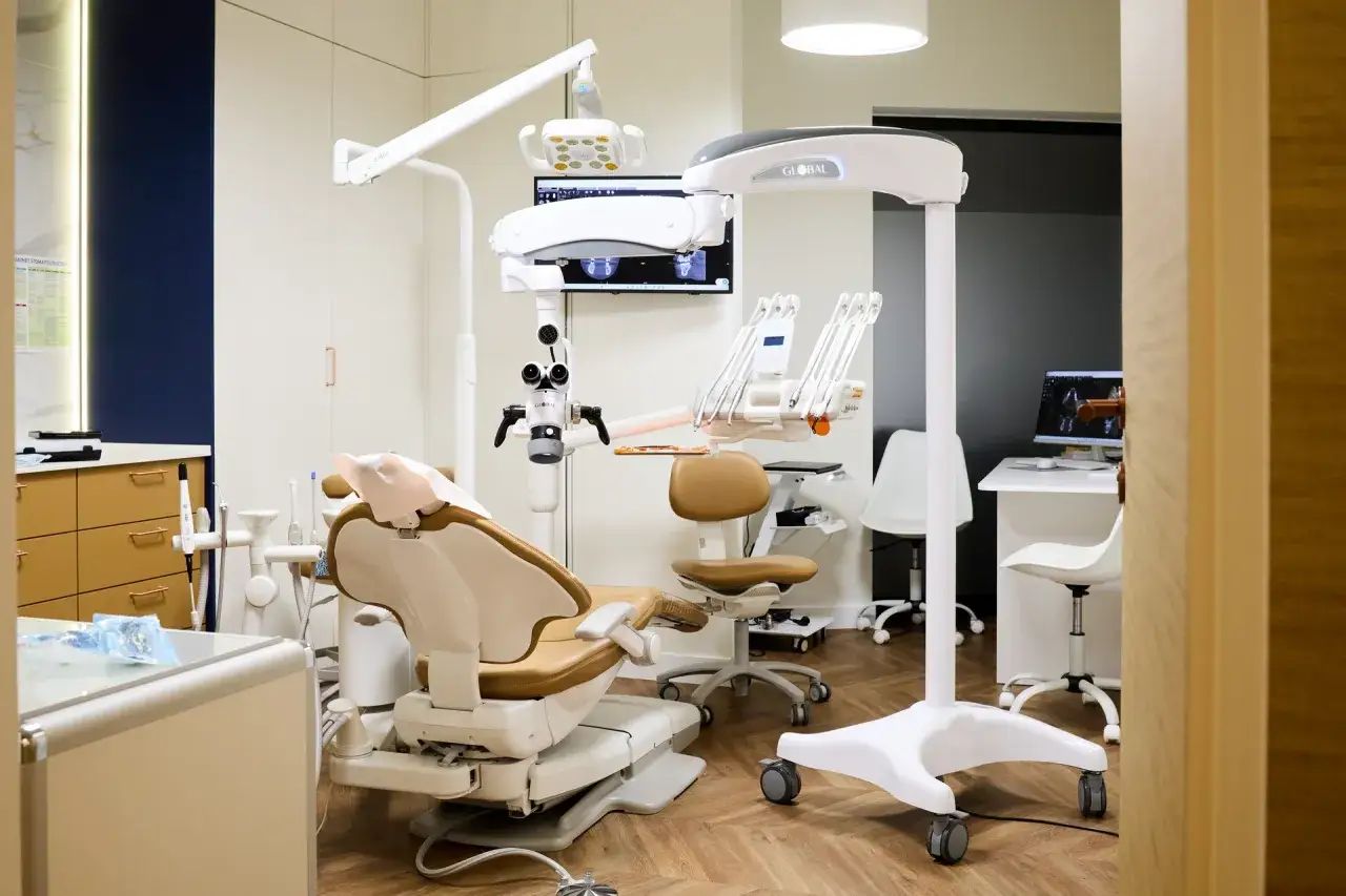 Nowoczesny gabinet stomatologiczny z fotelem, mikroskopem i sprzętem.