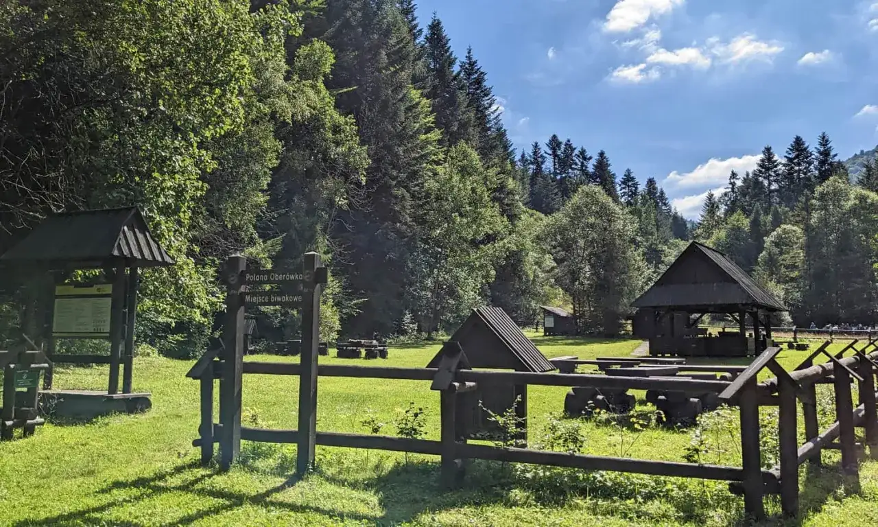 Polana Ober&oacute;wka na Turbaczu z Koninek. Drewniane wiaty i ławy zapraszają do odpoczynku wśr&oacute;d zieleni i lasu.