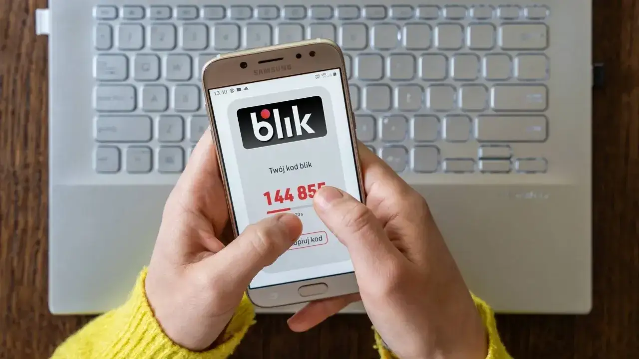 Ręce trzymają telefon z aplikacją Blik, pokazującą kod do transakcji. Szybki blik zwrot pieniędzy to wygoda.