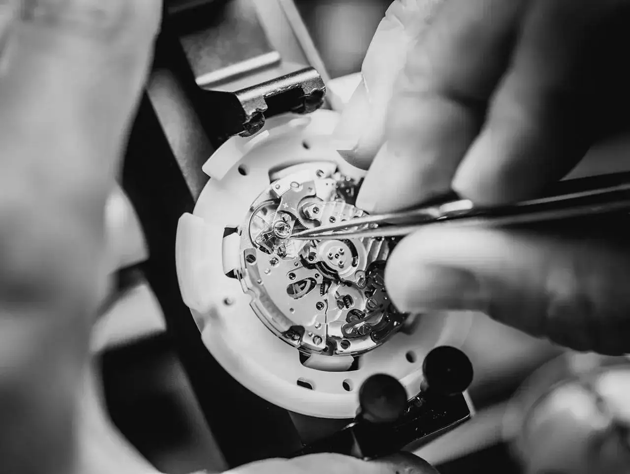 Dettaglio di un orologiaio che assembla con precisione un movimento meccanico, un capolavoro di ingegneria che porta il nome la joux perret.