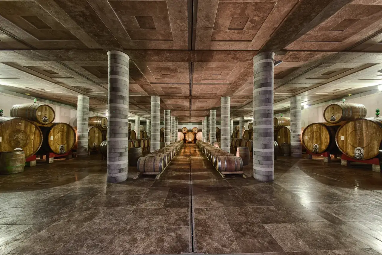 Cantine Montepulciano: un corridoio di botti di legno in una cantina sotterranea con colonne in pietra.