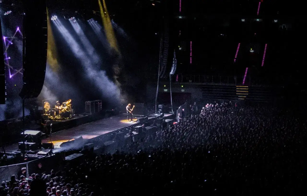 Koncert na Impact Festival. Gitarzysta gra na scenie, otoczony dymem i światłami. Tłum widzów wpatruje się w występ.