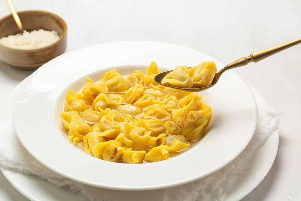 Un cucchiaio d'oro solleva un boccone di fumanti cappelletti in brodo, un classico piatto italiano.