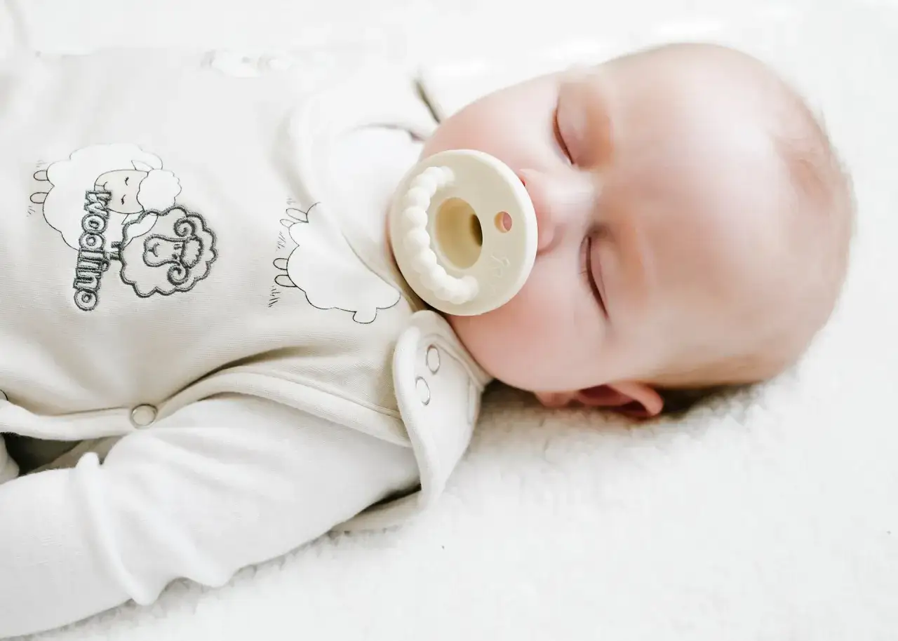 A peaceful baby sleeps with a pacifier, a common comfort. When can I give my baby a pacifier? This image shows a content infant, suggesting pacifiers can be used for soothing.