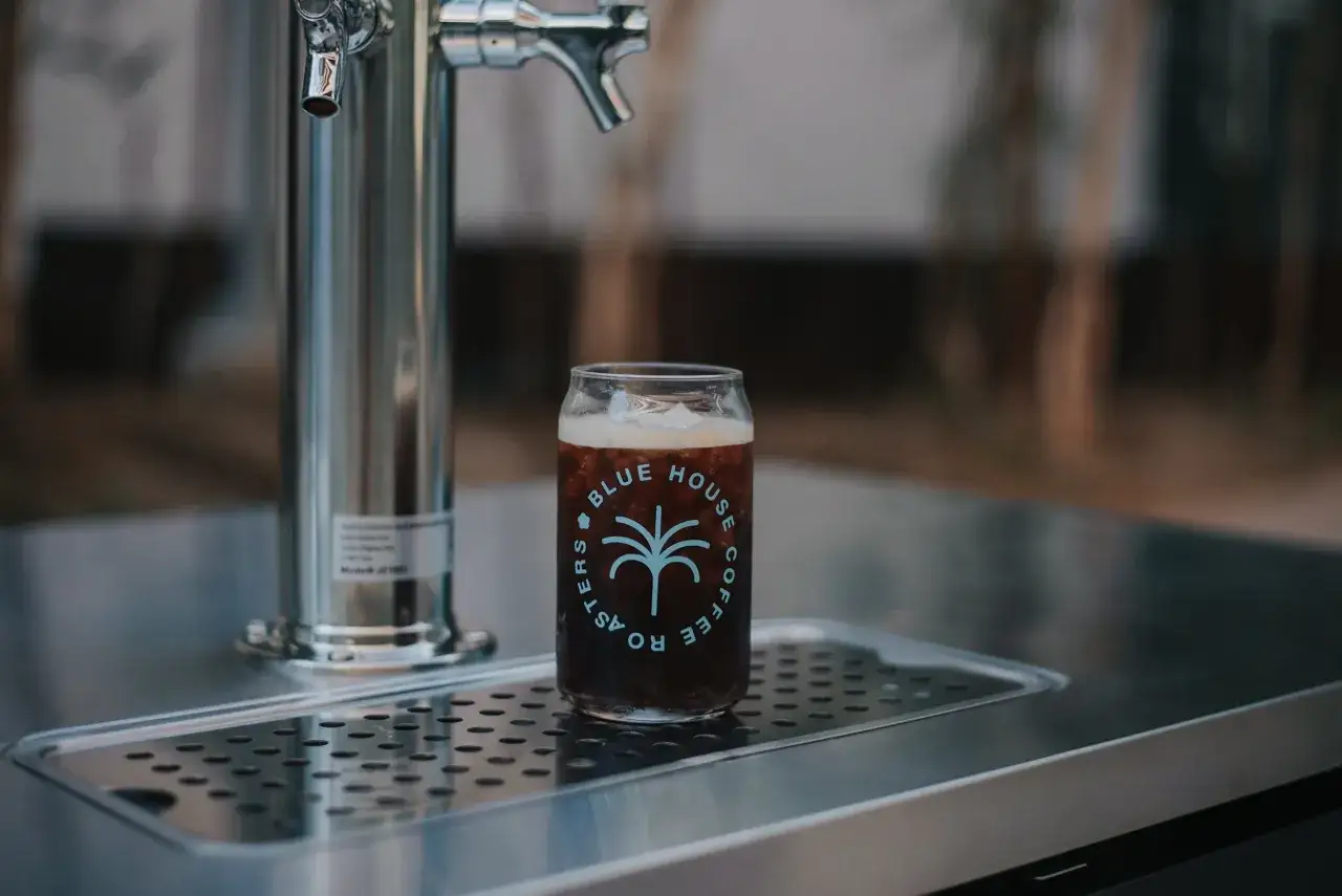 En glasburk med nitro cold brew kaffe st&aring;r bredvid en tappkran.