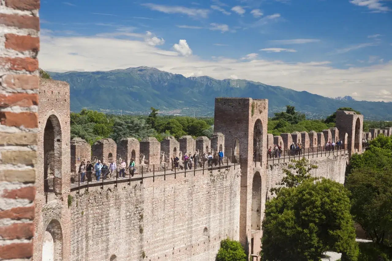 Passeggiata sulle mura della **cittadella** di Padova, con turisti che ammirano il panorama montuoso.