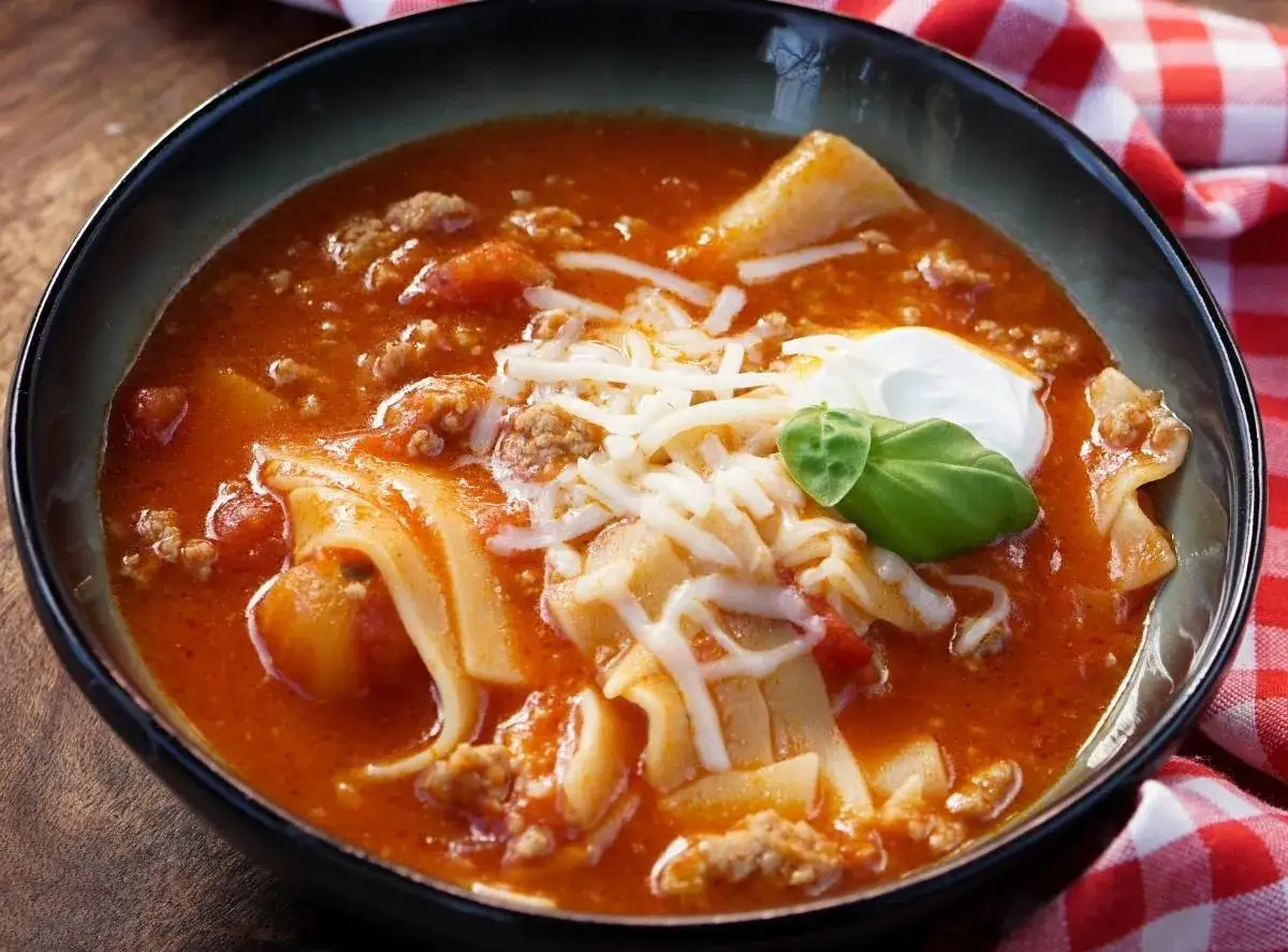 Herzhafte Lasagne Suppe mit Hackfleisch, Nudeln und Käse, garniert mit einem Klecks Sauerrahm und Basilikum.