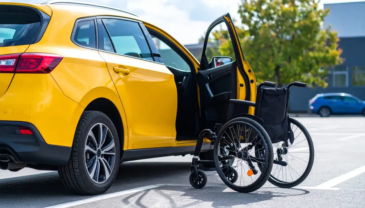 Auto gialla con portiera aperta e carrozzina. Un'opportunità per il passaggio di proprietà auto e detraibile.
