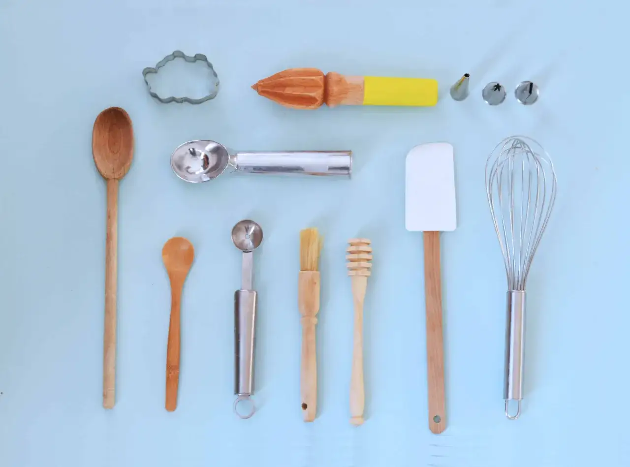 Ensemble d'ustensiles de pâtisserie : cuillères en bois, emporte-pièce, cuillère à glace, spatule, fouet, pinceau, etc. Tous les noms de materiel de patisserie sont présents.