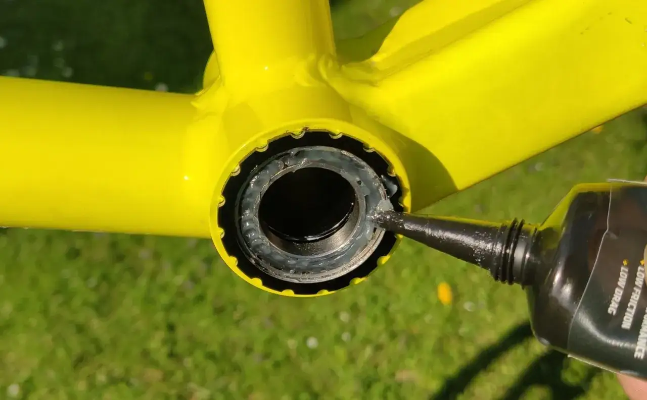 Smarowanie gwint&oacute;w przed wymianą suportu w rowerze.