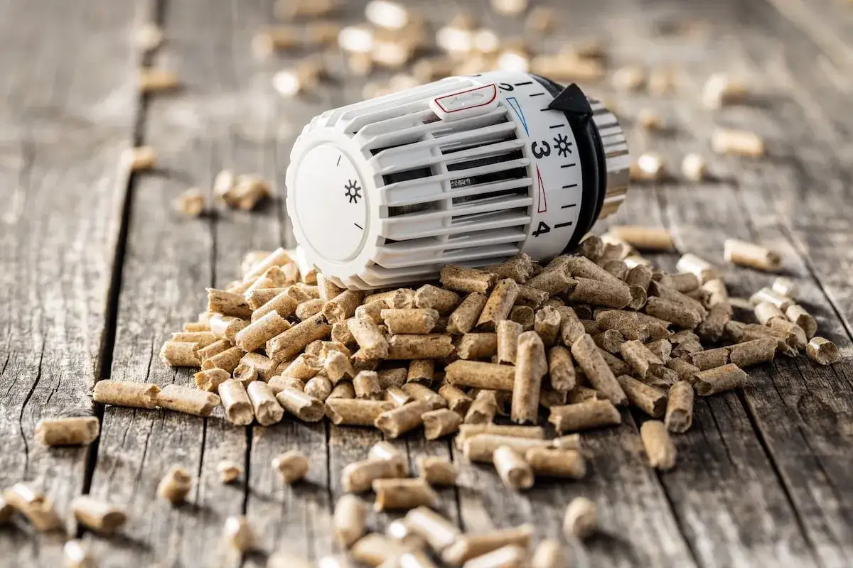 Heizungsregler auf Holzbrettern mit Pellets. Wie lange heizt man mit 15 kg Pellets?
