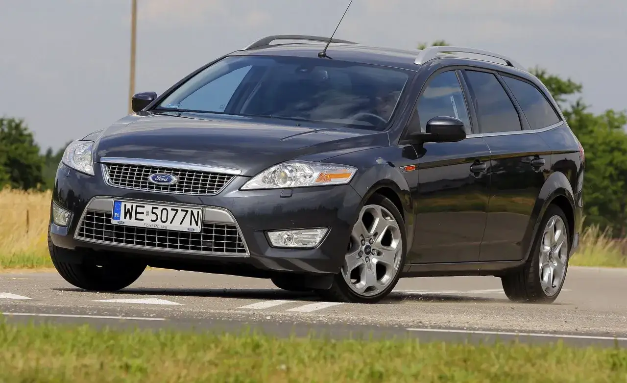 Ciemnoszary Ford Mondeo MK4 2.0 TDCI na zakręcie drogi, z widocznym polem zboża w tle.