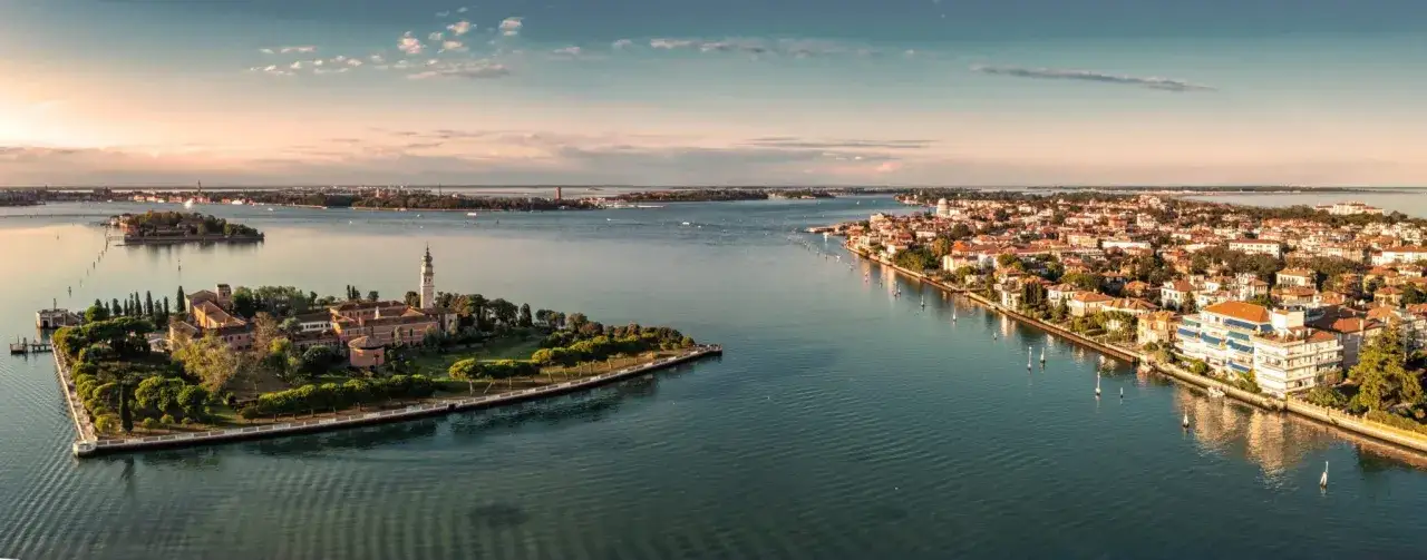 Isola di San Michele e la laguna di Venezia, con la città sullo sfondo. Un'incantevole vista di Venezia e dintorni al tramonto.