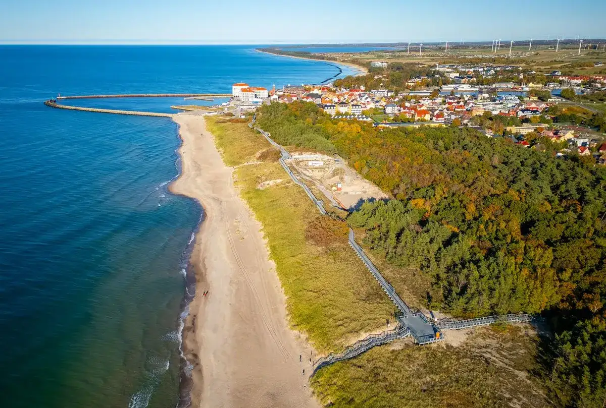 Widok na plażę i miasto, z falochronem i budynkami. Czy to Darłówko wschodnie czy zachodnie?