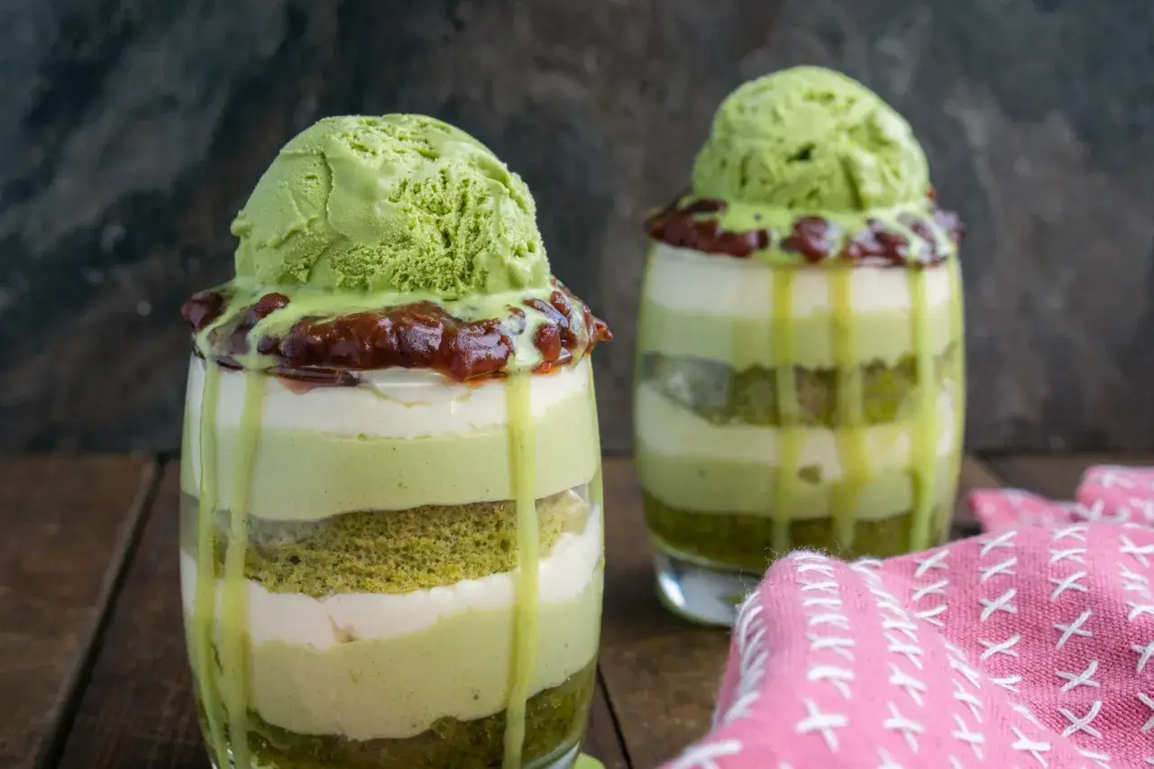 Deux coupes de glace au matcha latte, superposées avec de la crème et du gâteau.