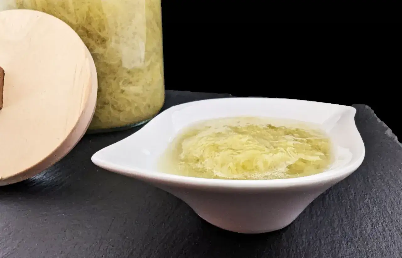 Une coupelle blanche sert une compote de rhubarbe onctueuse, à côté d'un bocal rempli de cette même préparation.
