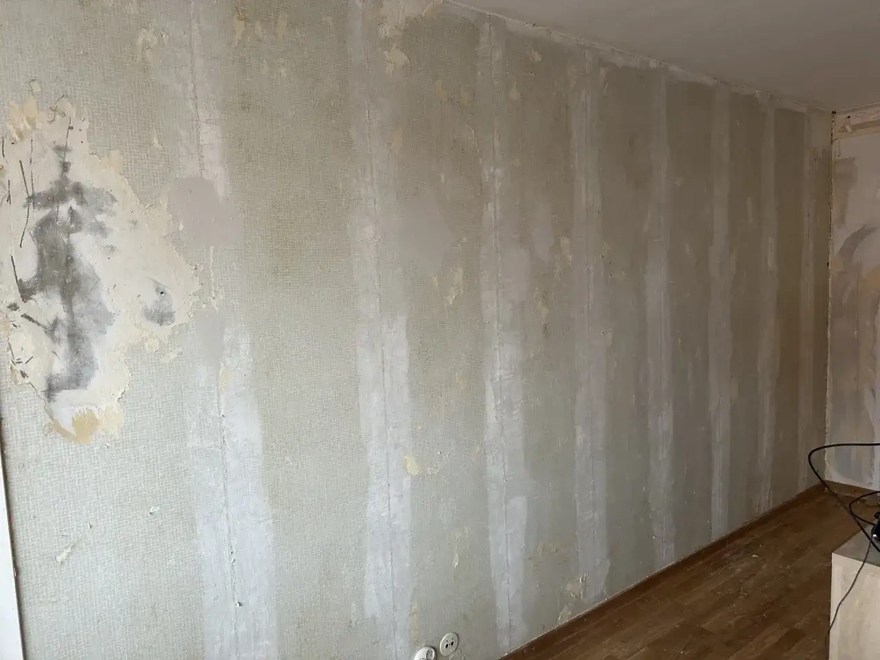 En vägg där gammal tapet är borttagen och man håller på att spackla på tapet för att jämna till ytan.