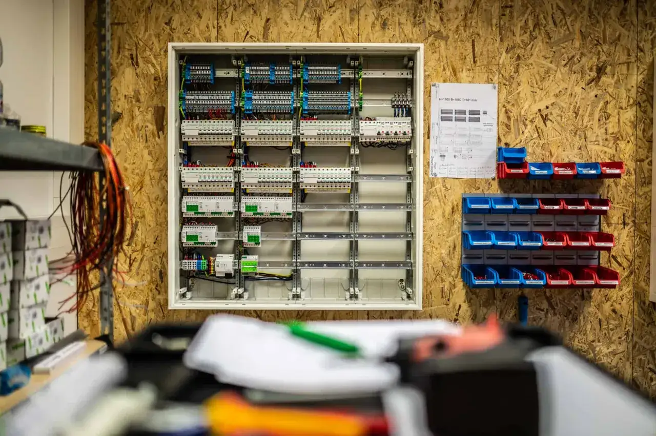 Detailaufnahme eines Schaltschranks, der f&uuml;r die **Smart Home Planung** vorbereitet wird. Daneben h&auml;ngen Kabel und eine Werkzeugwand mit Kleinteilen.
