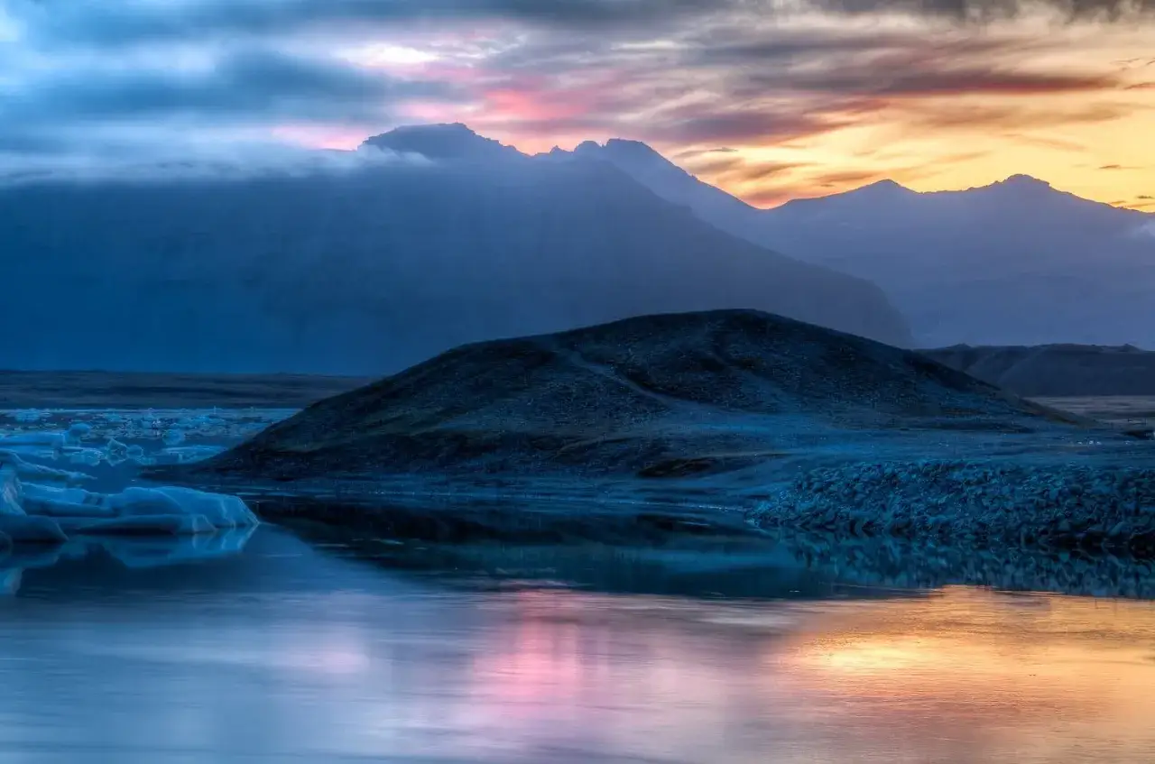 Paysage islandais au crépuscule, reflets roses et orangés sur l'eau, icebergs bleutés. Une photo HDR c'est quoi ? C'est cette richesse de détails.
